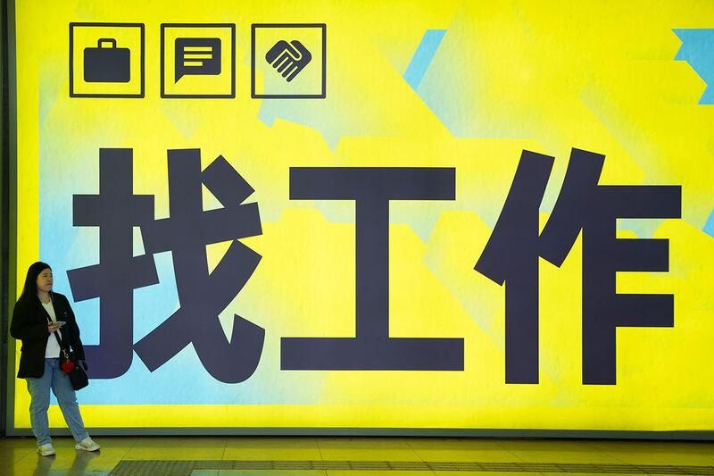 2024年7月2日,一名妇女站在北京一个地铁站张贴的"找工作"广告牌前。(美联社)