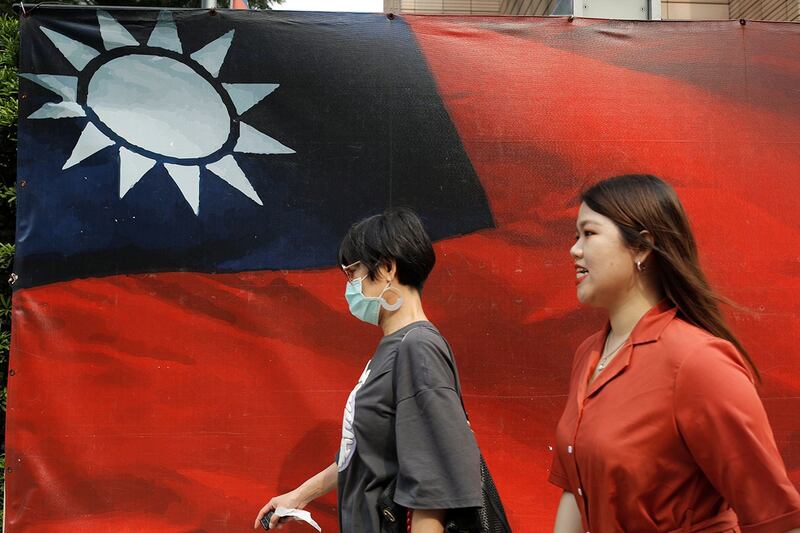 图为从台湾旗帜前走过的行人(路透社)